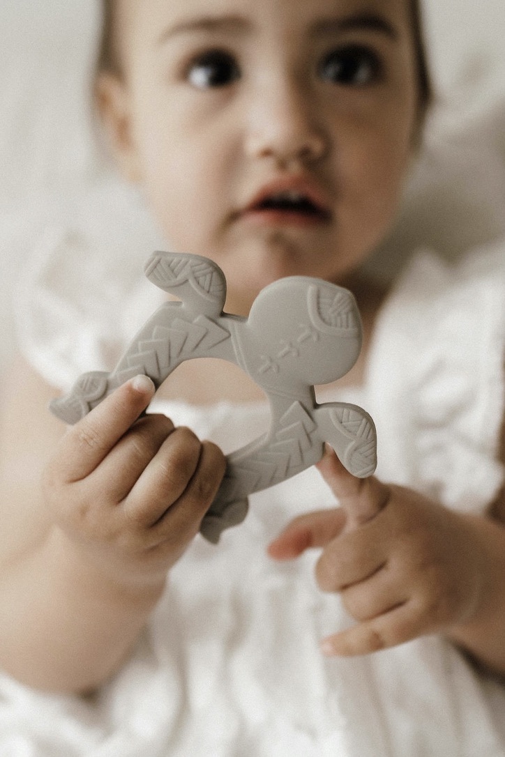Baby holding a turtle shaped polynesian inspired baby teether